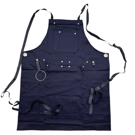 Dunkelblaue Arbeitsschürze aus robustem Stoff mit mehreren Taschen und Halterungen, darunter eine Brusttasche mit Reißverschluss, große Fronttaschen, Nietenverstärkungen, ein Metallring und verstellbare Bänder zum Binden. Ideal für Handwerk, Grillen oder Werkstattarbeiten.